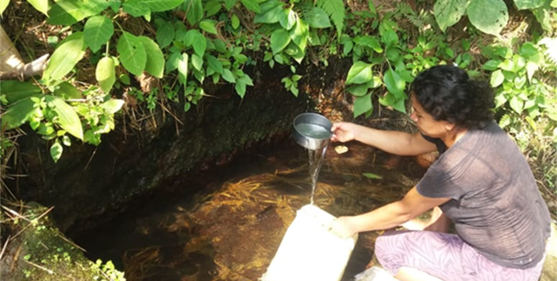 mujer coge agua de un río